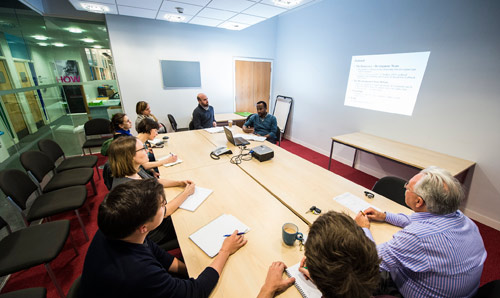 A photo of a postgraduate research student giving a presentation to academics.