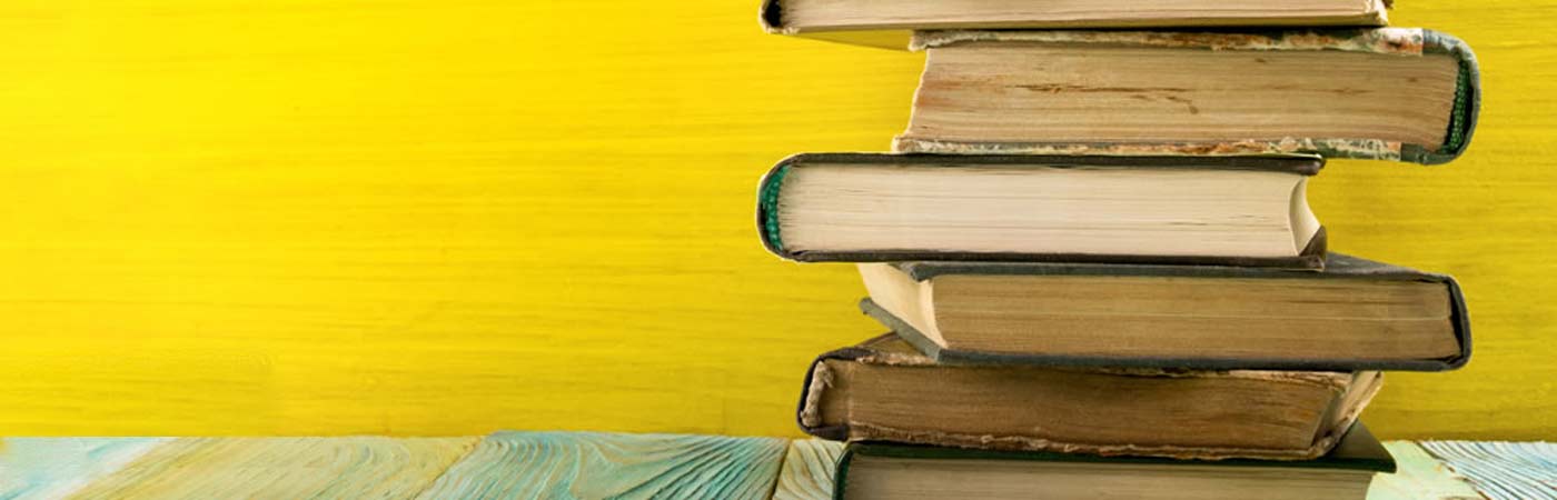 A pile of books on a shelf with a pastel background